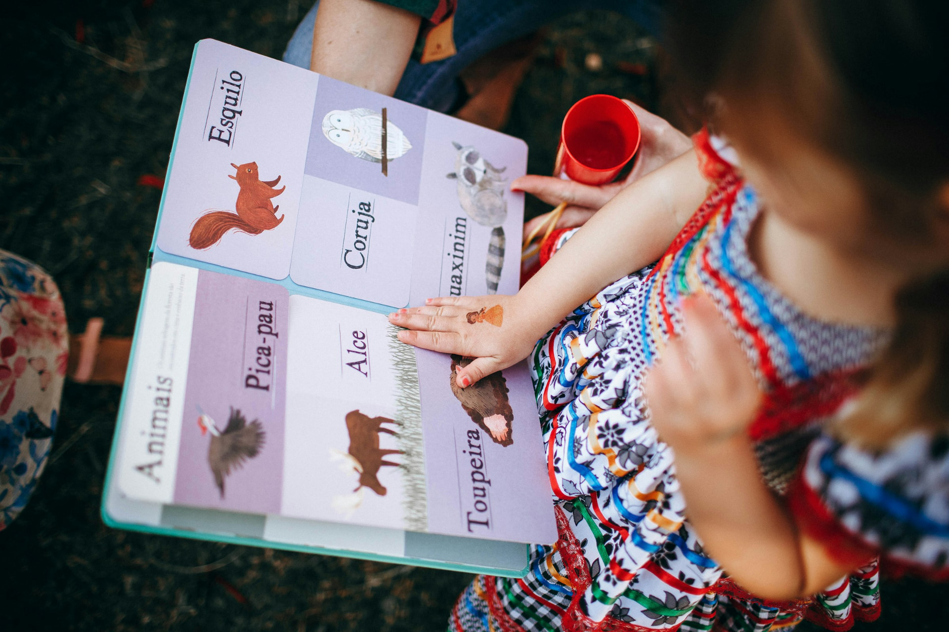 A child exploring an illustrated animal book with an adult