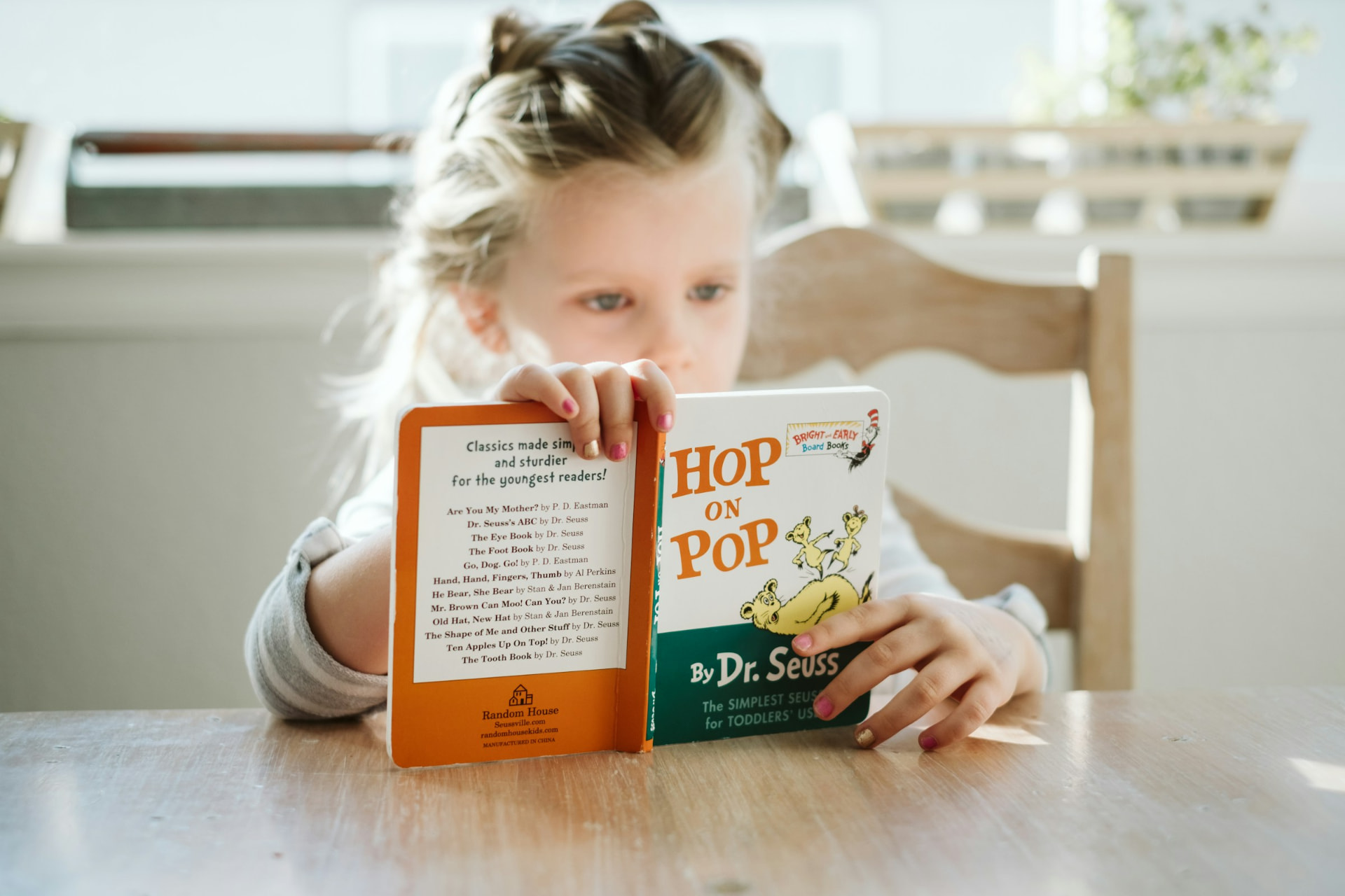 A young child reading a picture book at a table
